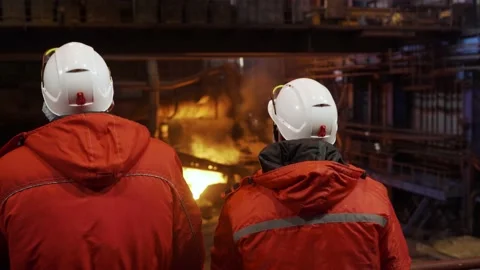 Workers in white helmets are standing in the shop of metallurgical production 動画素材 177384069