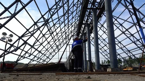 Workers in white helmets stand under the frame of a building metal structure Stock Footage 73815233
