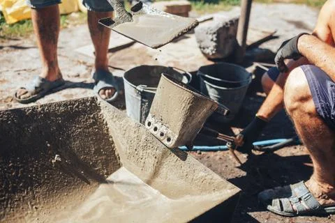 Workers work with cement mortar, loading the hopper bucket with mortar with a Stock-Fotos