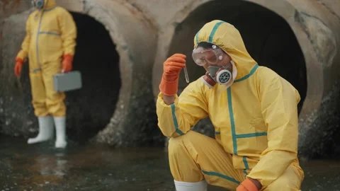 Workers in yellow suits inspect sewage pipes Stock Footage 346120388