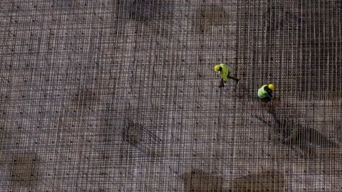 Workers in yellow uniform argue at construction site standing on rebars floor Video stock 236473793
