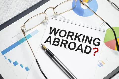 WORKING ABROAD. text on white paper. the inscription on the notebook Stock Photos