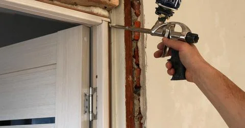 Working with an assembly gun when installing a door frame Stock Photos