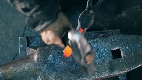 Working blacksmith hits a metal knife with a hammer on anvil. Stock Footage 114557561
