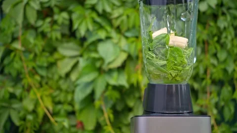 Working blander in the garden, making spinach banana detox smoothie Stock Footage 137932337