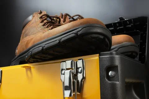 Working boots on yellow toolbox. Stock Photos