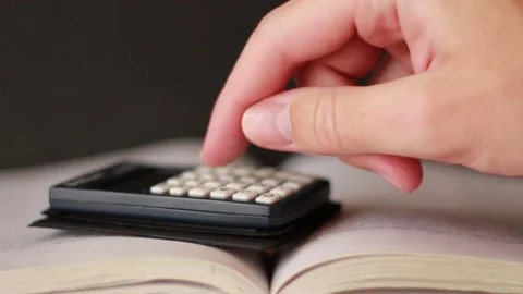 Working with calculator on book Stock Footage 75628916