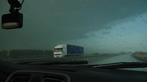 Working car wipers clearing windshield from raindrops on highway on trip. Stock Footage 254120053