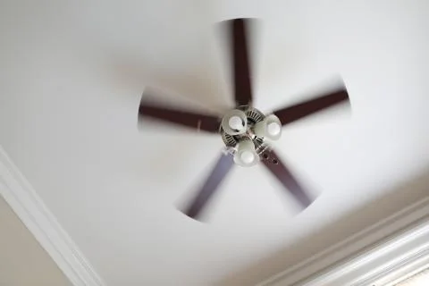 A working ceiling fan on a white ceiling, close up with blurred fan blades Stock Photos