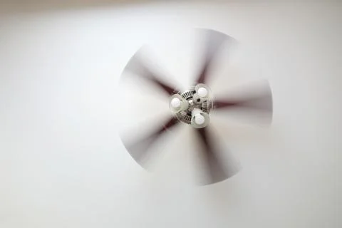 A working ceiling fan on a white ceiling, close up with blurred fan blades Stock Photos