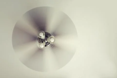 A working ceiling fan on a white ceiling, close up with blurred fan blades 스톡 사진