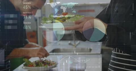Working chefs wearing aprons plating fresh salads on plates in restaurant Stock Photos
