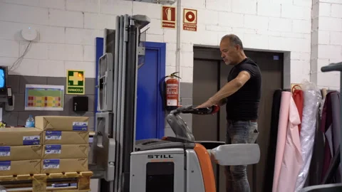 Working class caucasian labor driving an electric fork lifter for delivery 動画素材 263688311