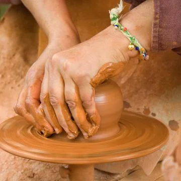 Working clay: womans hands making a pottery piece in a wheel Stock Photos