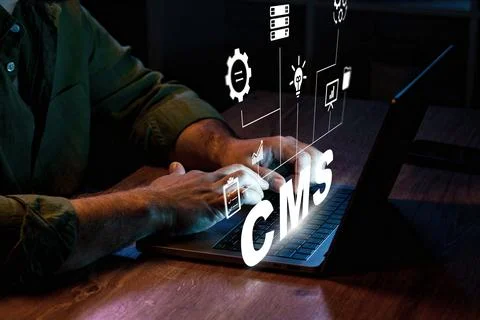 Working on CMS project at night with laptop and digital graphics on table 库存照片