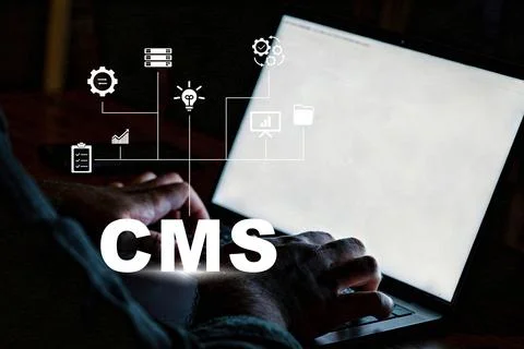Working on a computer in a dim room, focusing on content management system tasks Stock Photos