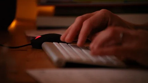Working on computer, hands with keyboard and mouse at home in the evening Stock Footage 98093744