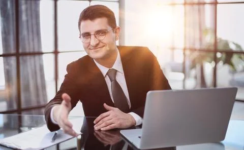Working at the computer, makes an inviting gesture, offers to sit down for an Foto stock