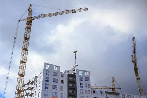 Working construction cranes and building. Rainy cloudy sky Stock Photos