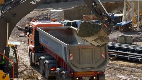 Working at a construction site, a truck backs up and excavator drops and soil Stock Footage 88665371