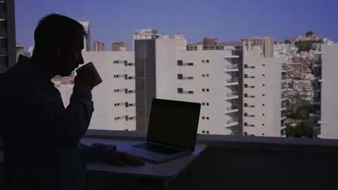 Working at a desk by the window while enjoying a drink with a view of the c.. 스톡 동영상 340189768