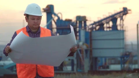 Working engineer in a helmet on the background of the company holding a drawing Stock Footage 95044438