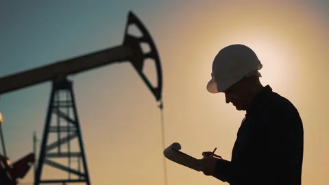 Working engineer.pump silhouette at sunset. An engineer works with tablet at an 動画素材 204841463