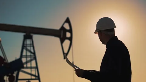 Working engineer.pump silhouette at sunset. An engineer works with tablet at an Stock Footage 252110119