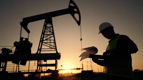 Working engineer.pump silhouette at sunset. An engineer works with tablet at an Stock Footage 257873883