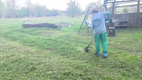 Working in the garden to clear grass and weeds in the early morning light on a r Stock Footage 336250888