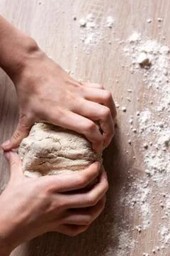 Working hands kneading bread dough. Wooden background Stock Photos