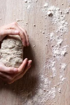 Working hands kneading bread dough. Wooden background Stock Photos