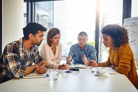 Working hard to meet their objectives. a team of designers having a meeting in Stock Photos