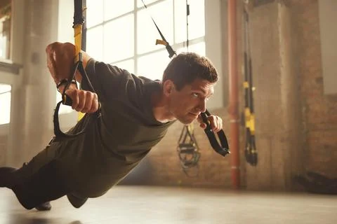 Working hard. Side view of young and strong athletic man in sportswear doing Stock Photos