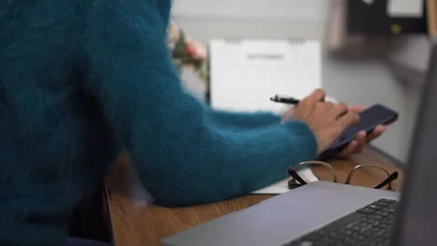 Working from home concept. Hand of Planner using phone and write daily agenda on 库存影片 146631973