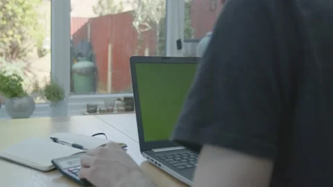 Working from home in the conservatory using a calculator with green screen Stockbeeldmateriaal 133805949
