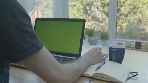 Working from home in the conservatory using a calculator writing in a notepad Stockbeeldmateriaal 133806037