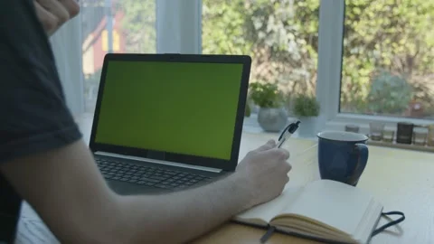Working from home in the conservatory writing in a notepad with green screen Stockbeeldmateriaal 133807629