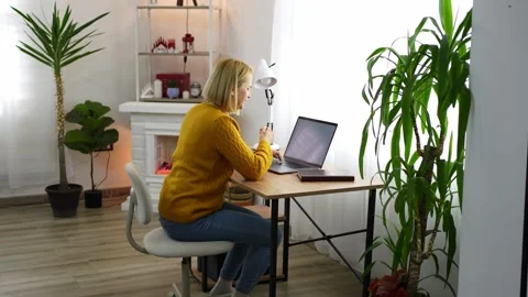 Working from home in a cozy and modern workspace with a touch of greenery and Stock Footage 305941603