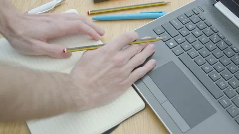 Working from home fiddling with a pencil with a notepad and laptop on dining Stockbeeldmateriaal 133808740