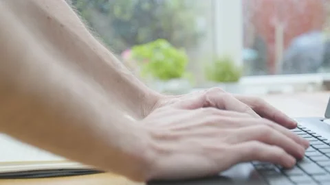 Working from home hands typing on a laptop on a dining table with a notepad  Stockbeeldmateriaal 133809494
