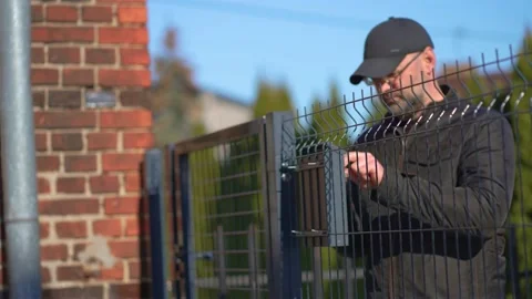 Working home installing post box for getting mail correspondence on metal fence Stock Footage 235195266