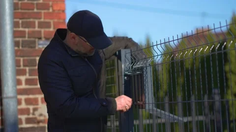 Working home installing post mailbox on metal fence outdoor Stock Footage 235701879