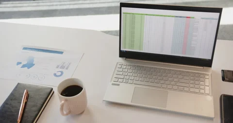 Working from home, laptop displaying spreadsheet next to coffee cup and Stock Footage 297750002
