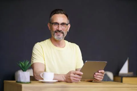 Working from home middle aged man use digital tablet sitting at home office desk Stock Photos