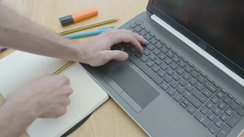 Working from home using a laptop holding a pencil thinking of what to write Stockbeeldmateriaal 133811068