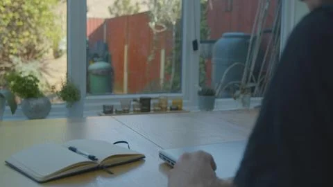 Working from home using a notepad on the dinner table Foto stock