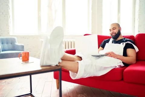 Working at home. Young man using laptop computer while sitting on sofa. Foto stock