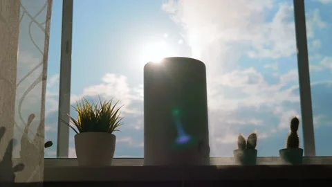 A working humidifier stands on the window while sunlight shines on it. Stock Footage 241406249