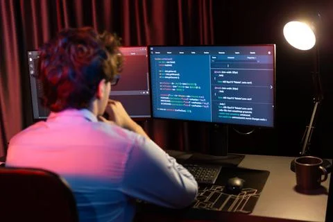 Working IT developer concentrating online software at neon light room. Gusher. Stock Photos